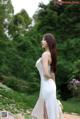 A woman in a white dress standing in a park.