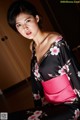 A woman in a black and pink kimono posing for a picture.