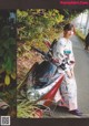 A woman in a kimono standing next to a motorcycle.