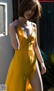 A woman in a yellow dress posing for a picture.