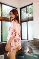 A woman in a pink kimono standing in a bathtub.