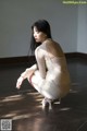 A woman in a white dress crouching on the floor.