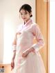 A woman in a pink and white hanbok is posing for a picture.