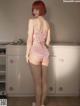 A woman in a pink lingerie standing in a kitchen.