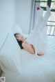 A woman laying on a bed in a white dress.